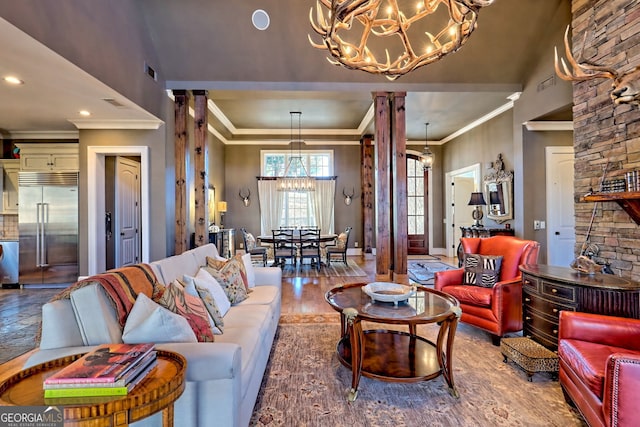 living room featuring decorative columns, crown molding, hardwood / wood-style flooring, and a notable chandelier