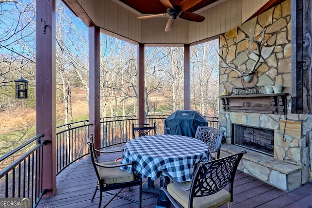 sunroom with ceiling fan and an outdoor stone fireplace