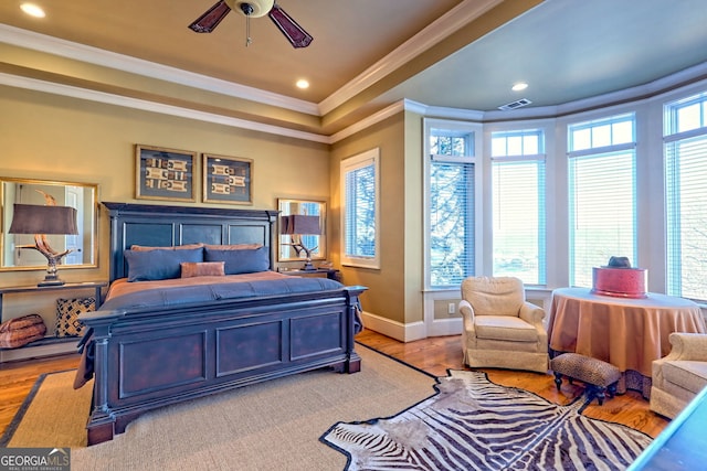 bedroom with multiple windows, ornamental molding, ceiling fan, and light hardwood / wood-style floors