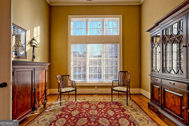 living area featuring ornamental molding and light wood-type flooring