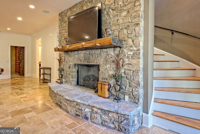 living room with ornamental molding and a stone fireplace