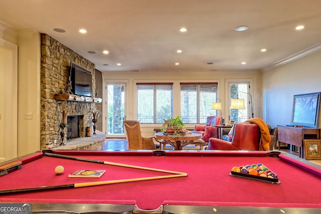 recreation room featuring billiards, ornamental molding, and a stone fireplace