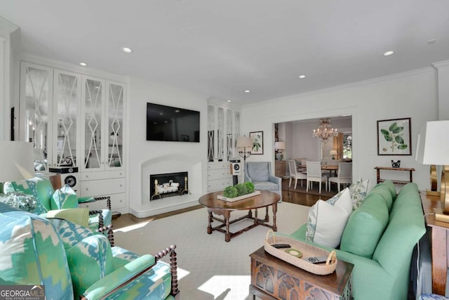 living room featuring a notable chandelier, wood-type flooring, and ornamental molding