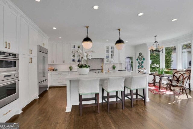 kitchen featuring dark wood-type flooring, pendant lighting, a notable chandelier, and a kitchen bar