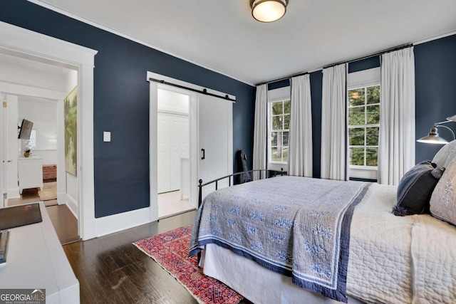 bedroom with a barn door and dark hardwood / wood-style flooring