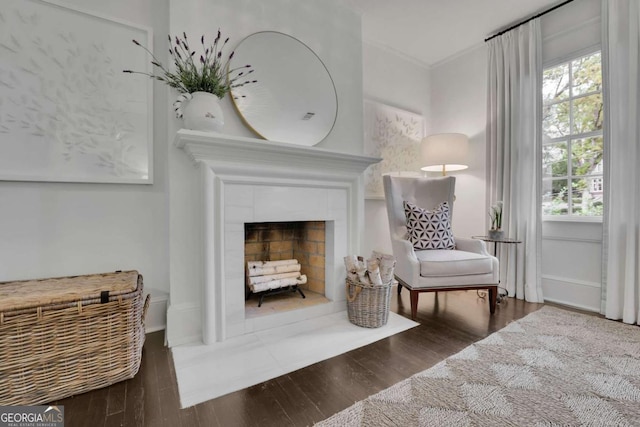 living area with ornamental molding, a fireplace, and dark hardwood / wood-style flooring