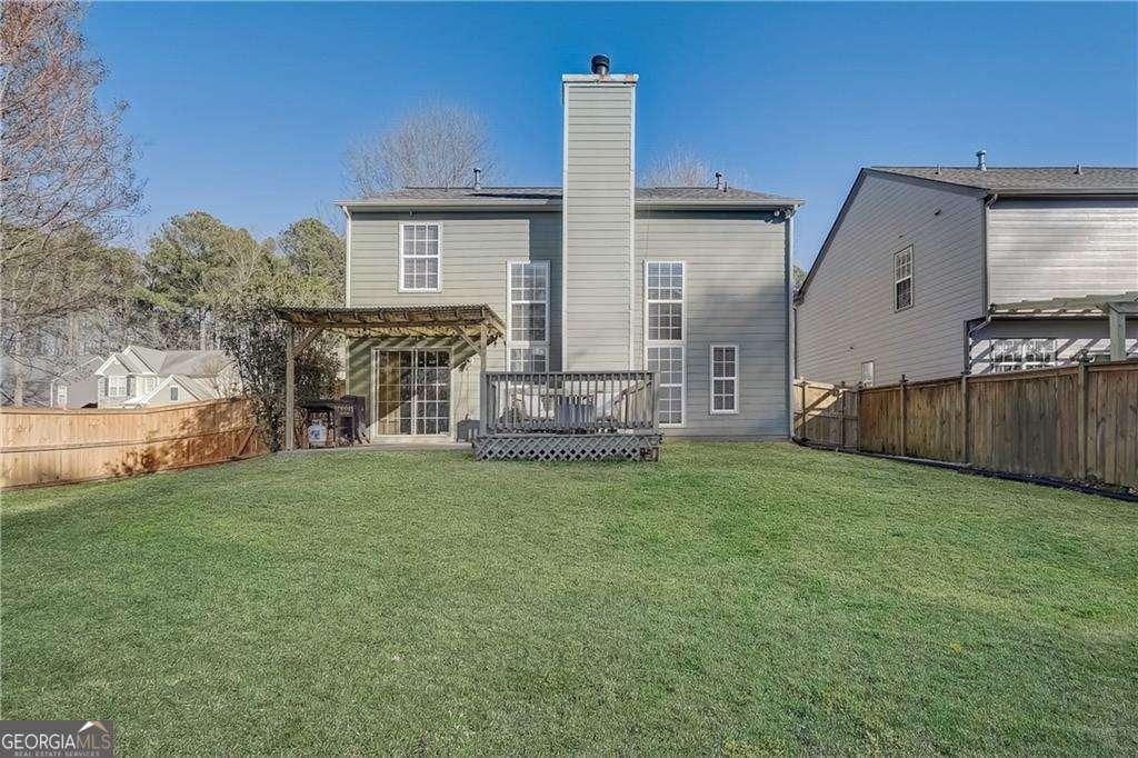 rear view of property with a wooden deck, a yard, and a pergola