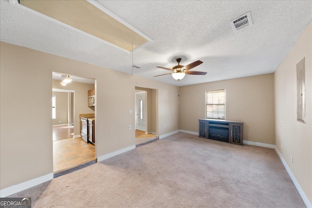 unfurnished living room with ceiling fan, a fireplace, light carpet, and a textured ceiling