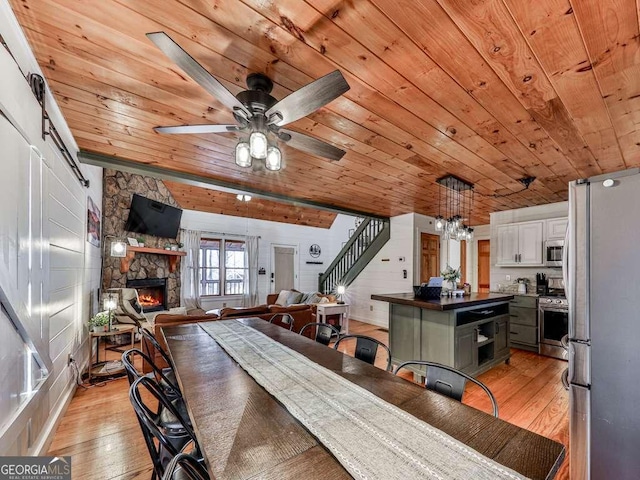 dining space with wood ceiling, ceiling fan with notable chandelier, and light hardwood / wood-style floors