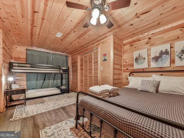 bedroom with wood ceiling, wooden walls, a closet, and wood-type flooring