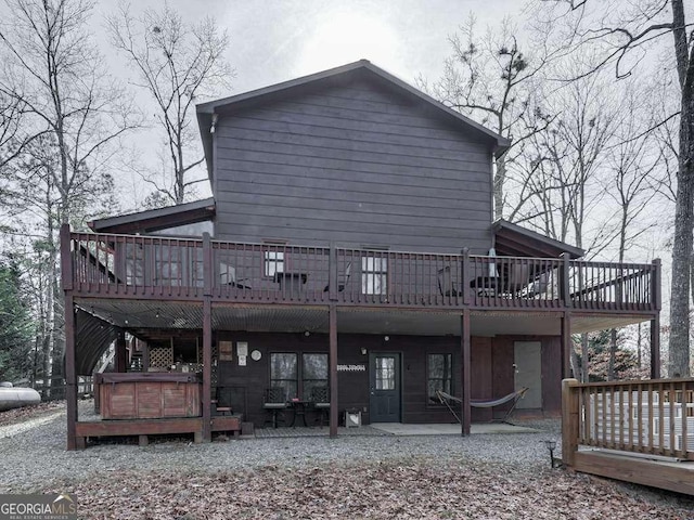 back of house featuring a hot tub, a wooden deck, and a patio