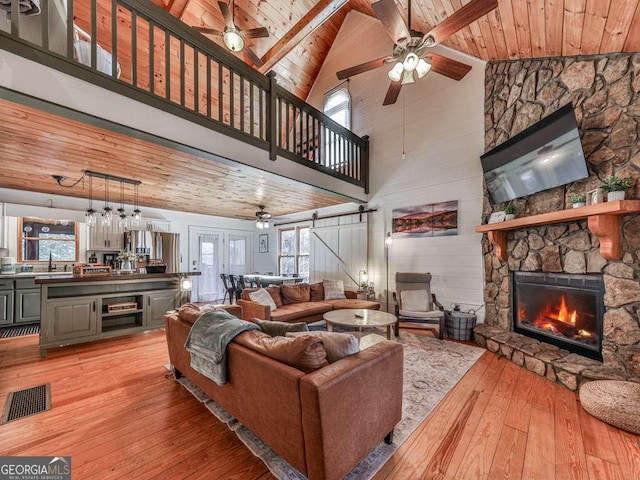 living room with wood ceiling, plenty of natural light, a barn door, and light hardwood / wood-style flooring