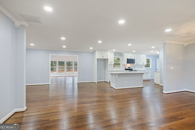 unfurnished living room with baseboards, visible vents, recessed lighting, ornamental molding, and dark wood-type flooring