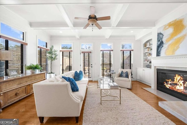 living room with beam ceiling, a healthy amount of sunlight, built in features, and light wood-type flooring