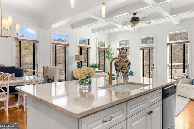 kitchen with sink, light stone countertops, decorative light fixtures, stainless steel dishwasher, and beamed ceiling