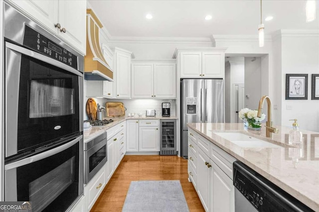 kitchen with appliances with stainless steel finishes, white cabinetry, ornamental molding, decorative light fixtures, and beverage cooler