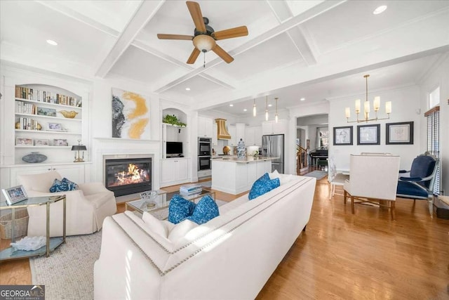 living room with beam ceiling, coffered ceiling, light hardwood / wood-style floors, and built in shelves