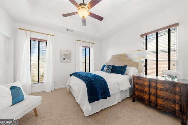 carpeted bedroom featuring ceiling fan and a tray ceiling