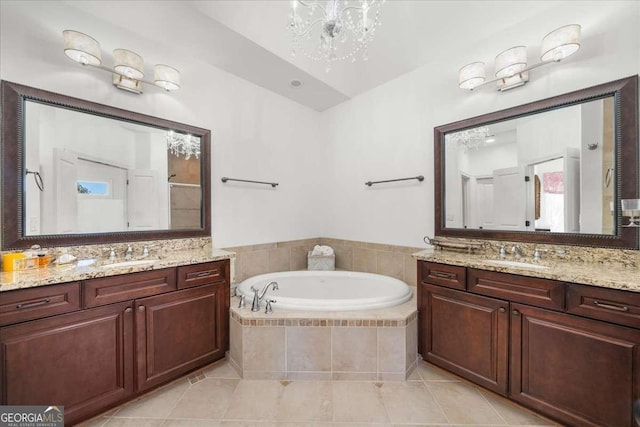 bathroom featuring a notable chandelier, vanity, tiled bath, and tile patterned floors