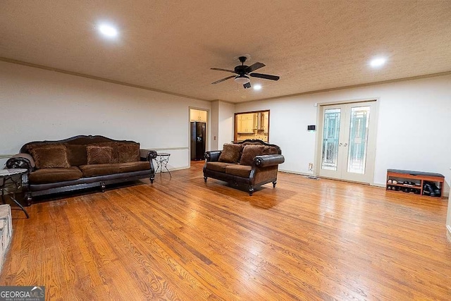 living room featuring ceiling fan, light wood-type flooring, a textured ceiling, and french doors