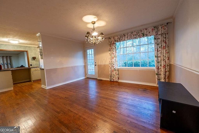 unfurnished dining area with an inviting chandelier, crown molding, wood-type flooring, and a textured ceiling