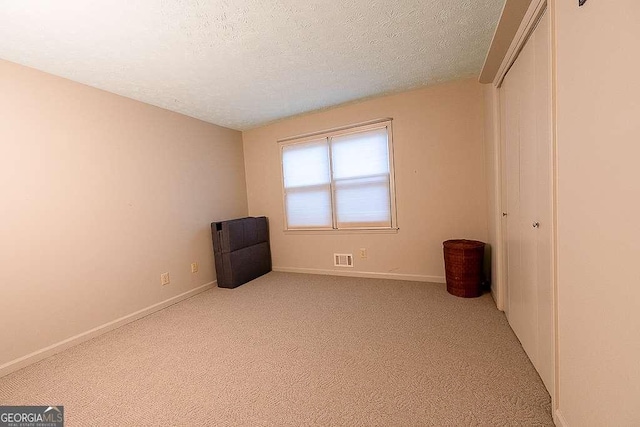 unfurnished bedroom featuring light carpet and a textured ceiling