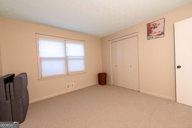 bedroom featuring light carpet, a textured ceiling, and a closet