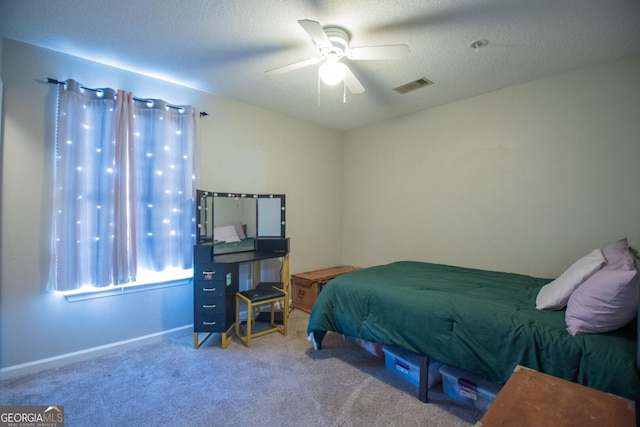 carpeted bedroom featuring ceiling fan and a textured ceiling