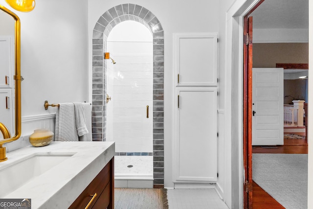 bathroom with tiled shower and vanity