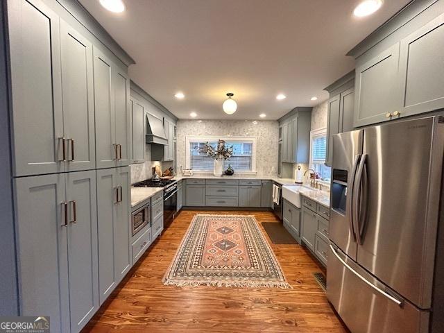 kitchen with sink, premium range hood, gray cabinetry, hardwood / wood-style floors, and stainless steel appliances