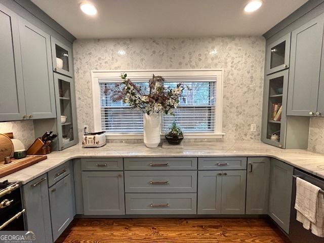 kitchen featuring dark wood-type flooring, dishwasher, gray cabinets, and light stone counters