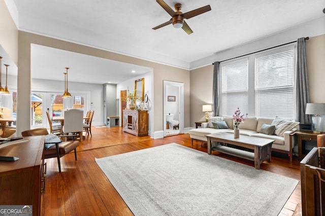 living room featuring wood-type flooring, ornamental molding, and ceiling fan