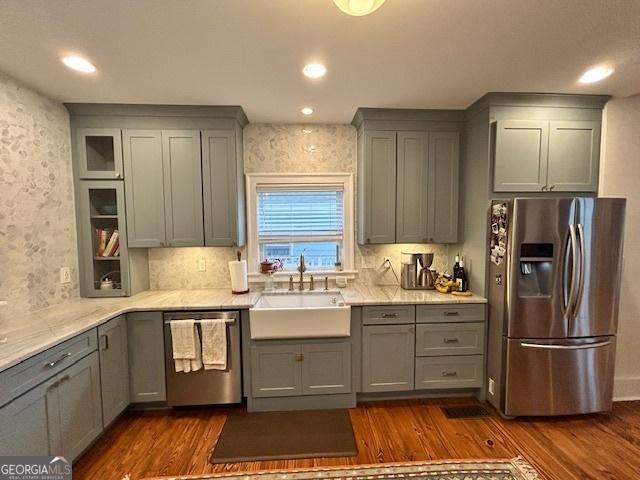 kitchen featuring dark hardwood / wood-style floors, sink, backsplash, light stone counters, and stainless steel appliances