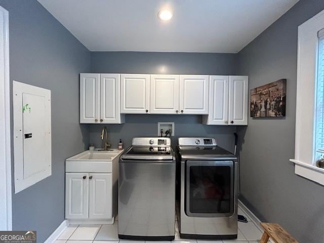 laundry area featuring light tile patterned flooring, washing machine and clothes dryer, sink, cabinets, and electric panel