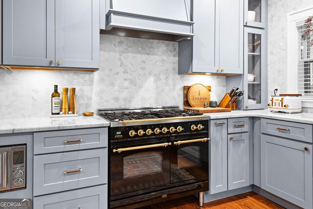 kitchen with light stone counters, gray cabinets, and range with two ovens