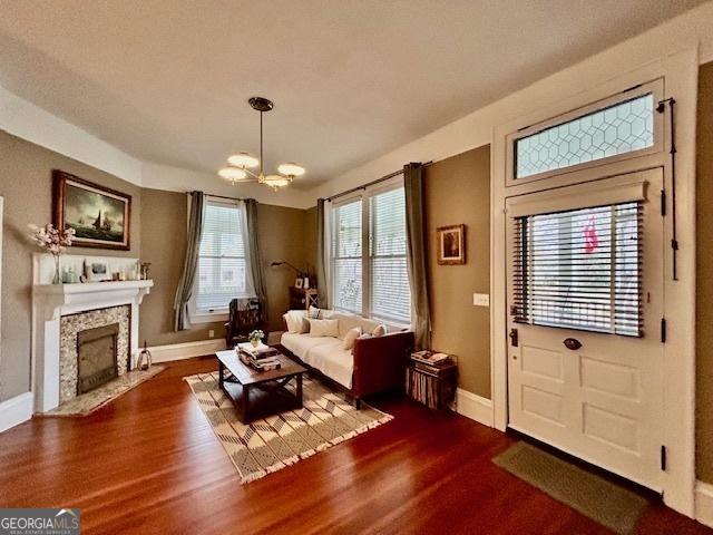 living room with dark wood-type flooring, a fireplace, and a notable chandelier