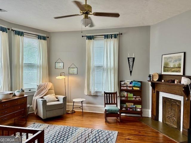 sitting room with hardwood / wood-style floors and ceiling fan