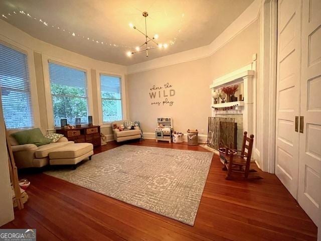 living area featuring hardwood / wood-style flooring, a brick fireplace, and an inviting chandelier