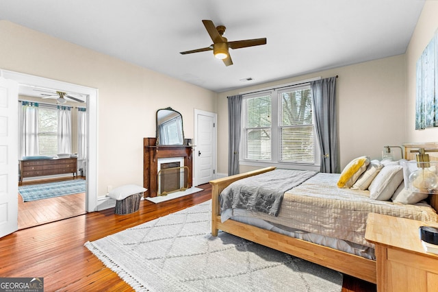 bedroom with ceiling fan, multiple windows, and light hardwood / wood-style flooring