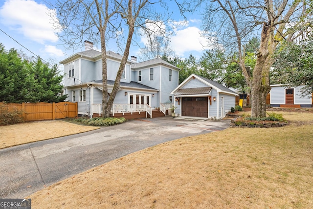 view of property with an outbuilding, a wooden deck, a garage, and a front yard