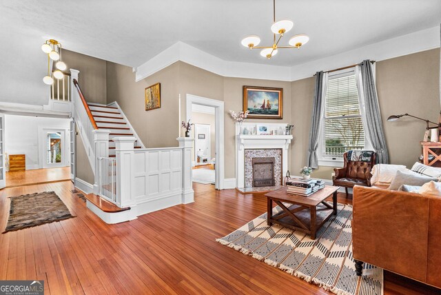 living room with hardwood / wood-style floors, a tile fireplace, and a chandelier