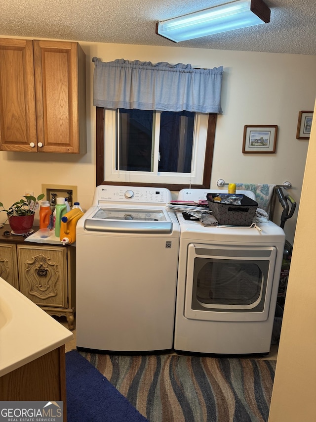 laundry area featuring cabinets, a textured ceiling, and washer and clothes dryer