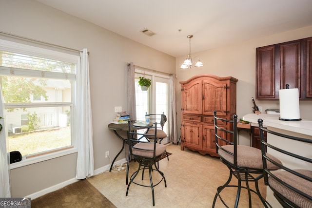 dining room with an inviting chandelier, built in desk, and a healthy amount of sunlight