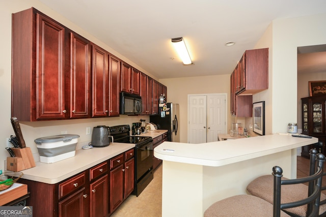 kitchen featuring a breakfast bar, kitchen peninsula, and black appliances