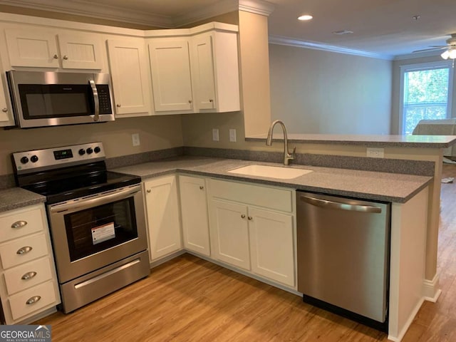 kitchen with sink, kitchen peninsula, stainless steel appliances, light hardwood / wood-style floors, and white cabinets