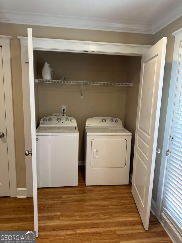 laundry area with crown molding, separate washer and dryer, and light hardwood / wood-style floors