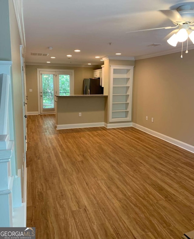 unfurnished living room featuring crown molding, wood-type flooring, and ceiling fan