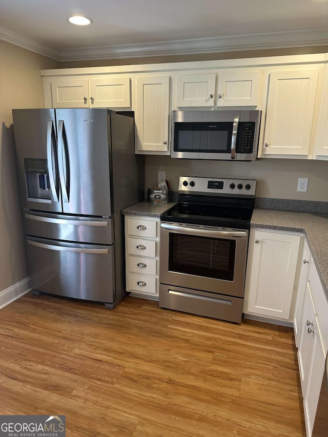 kitchen featuring stainless steel appliances, crown molding, white cabinets, and light hardwood / wood-style flooring