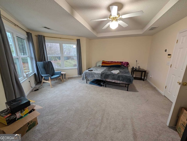 bedroom featuring light carpet, a textured ceiling, a raised ceiling, and visible vents