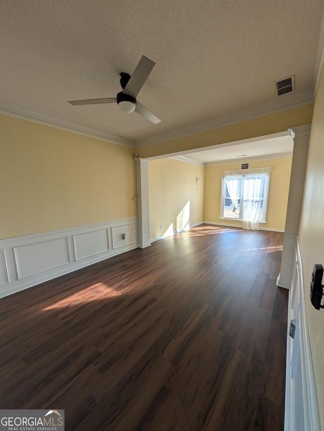 unfurnished living room featuring a textured ceiling, dark wood-type flooring, a ceiling fan, visible vents, and crown molding